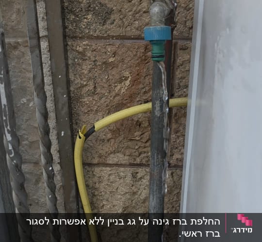 ברז מים עם צינור צהוב על קיר אבן